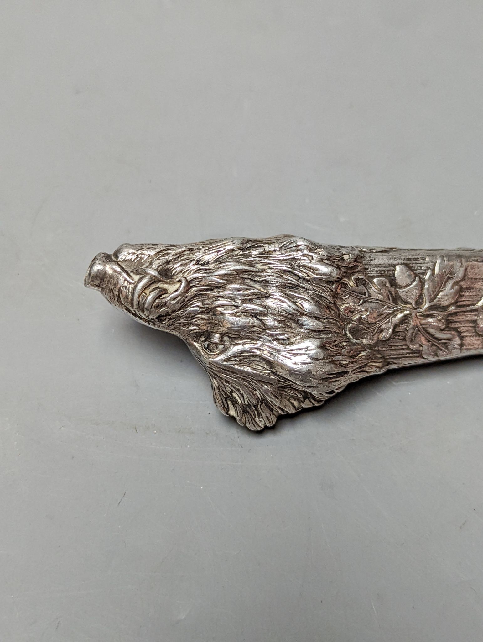 An Austro Hungarian white metal mounted cigar cutter, modelled as the head of a wild boar with acorn leaves, 13.9cm.